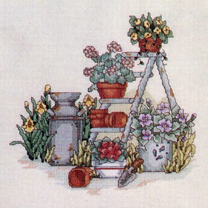 Peut inclure: Motif de point de croix d'une scène de jardin avec une cruche en métal vieilli, une petite échelle supportant des plantes en pot et diverses fleurs. La palette de couleurs comprend des verts, des jaunes, des rouges et des violets, créant une esthétique charmante et rustique.