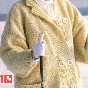 May include: A light yellow, double-breasted knitted coat with large white buttons and two front pockets. The coat is worn with a white beret, scarf, and gloves. A black ski pole is held in the hand.