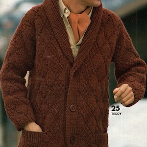 以下が含まれることがあります： 菱形模様のダークブラウンの長袖カーディガン。2つのポケットと3つのボタンが付いています。明るい色のシャツとオレンジ色のスカーフの上に着用。ツイードの帽子をかぶっています。「25 TEDDY」の文字が見えます。