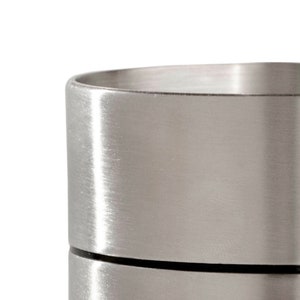 May include: A silver metal container with a brushed finish. The container has a lid and is made of two separate pieces.