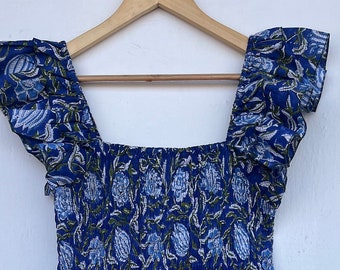 Peut inclure: Une robe à fleurs bleues avec un corsage smocké et des bretelles à volants. La robe a une jupe à volants et une coupe ample.