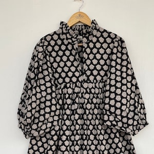 May include: A black and white floral print midi dress with a ruffled neckline and 3/4 sleeves.