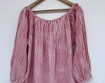 May include: A red and white striped off-the-shoulder dress with long sleeves. The dress is made of a lightweight fabric and has a loose, flowing fit.