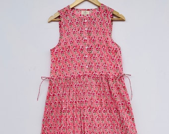 May include: A pink sleeveless maxi dress with a floral print and a button-up front. The dress has a tiered skirt and ties at the waist.