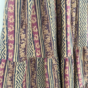 May include: A beige, pink, and blue striped fabric with a floral pattern. The fabric has a tiered design.
