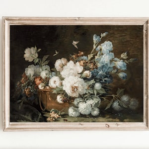 Peut inclure: Une peinture à l'huile encadrée représentant une nature morte de fleurs blanches et bleues dans un vase en cuivre. Les fleurs sont disposées dans un vase sur un fond sombre. La peinture est encadrée dans un cadre en bois clair.