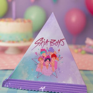 May include: A triangular party hat with a purple and blue watercolor design. The hat features the text "Saja Boys" and an illustration of a group of people. The bottom edge has a purple, corrugated trim. Party decorations are in the background.