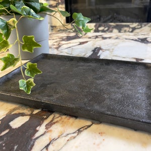 May include: A black rectangular tray made of a textured material. The tray is sitting on a marble surface.