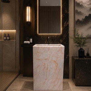 Puede incluir: Un lavabo de ba&ntilde;o rectangular independiente fabricado en m&aacute;rmol rosa claro con vetas anaranjadas sutiles. El lavabo presenta un acabado liso y pulido con una silueta geom&eacute;trica limpia, posicionado centralmente en un ba&ntilde;o moderno.