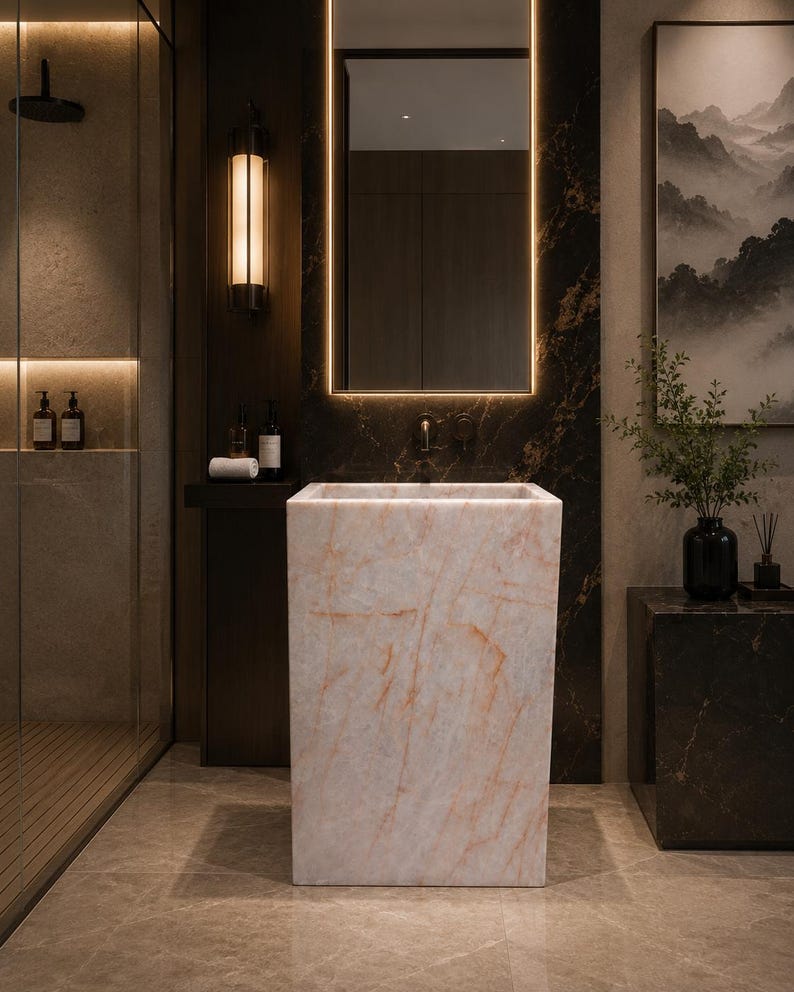 Puede incluir: Un lavabo de ba&ntilde;o rectangular independiente fabricado en m&aacute;rmol rosa claro con vetas anaranjadas sutiles. El lavabo presenta un acabado liso y pulido con una silueta geom&eacute;trica limpia, posicionado centralmente en un ba&ntilde;o moderno.