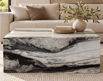 May include: A low, rectangular coffee table crafted from white marble with prominent, sweeping black veining throughout its surface. The table features a solid, block-like construction with a smooth, polished finish that highlights the natural stone patterns.