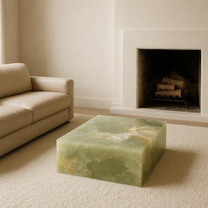 May include: A rectangular coffee table crafted from solid green onyx stone, featuring a smooth, polished surface with natural white and amber veining patterns throughout the block-like structure, resting on a textured off-white carpet floor.