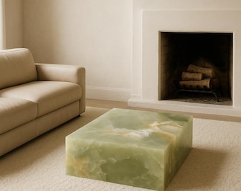 May include: A rectangular coffee table crafted from solid green onyx stone, featuring natural swirling patterns in shades of pale green, white, and amber. The piece has a smooth, polished finish with sharp, clean edges and a block-like structure.