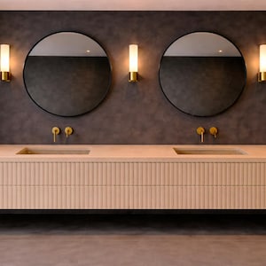 Könnte beinhalten: Modernes Badezimmerdesign mit einem schwebenden Waschtisch mit geriffelter Front, zwei runden Spiegeln und goldenen Armaturen. Der Waschtisch hat zwei Waschbecken und befindet sich vor einer dunkelgrauen Wand mit Wandleuchten.