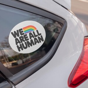 A car sticker on a back window that reads "We are all human"