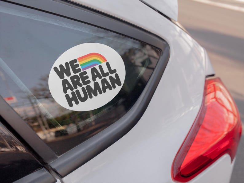 A car sticker on a back window that reads "We are all human"