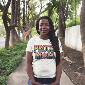 A black mom on a path wearing a t-shirt that reads "proud mom" with rainbow colored text and a heart graphic
