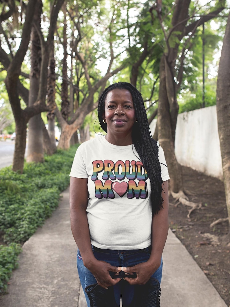 A black mom on a path wearing a t-shirt that reads "proud mom" with rainbow colored text and a heart graphic