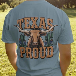 A man wearing a blue shirt that says "Texas Proud" with a longhorn and bluebonnet graphics