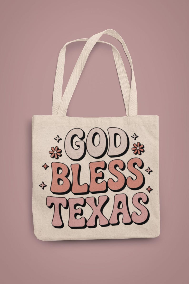 A white canvas tote bad that reads "god bless texas"