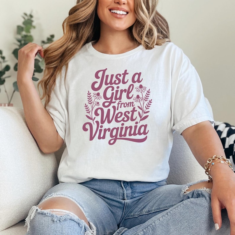 a woman wearing a white tshirt that says "Just a girl from West Virginia" with floral graphics. this design is part of A collection of west virginia vector designs perfect for cricut, silhouette, sublimation, DTF Printing, POD, tshirts, mugs, tote bags and more!