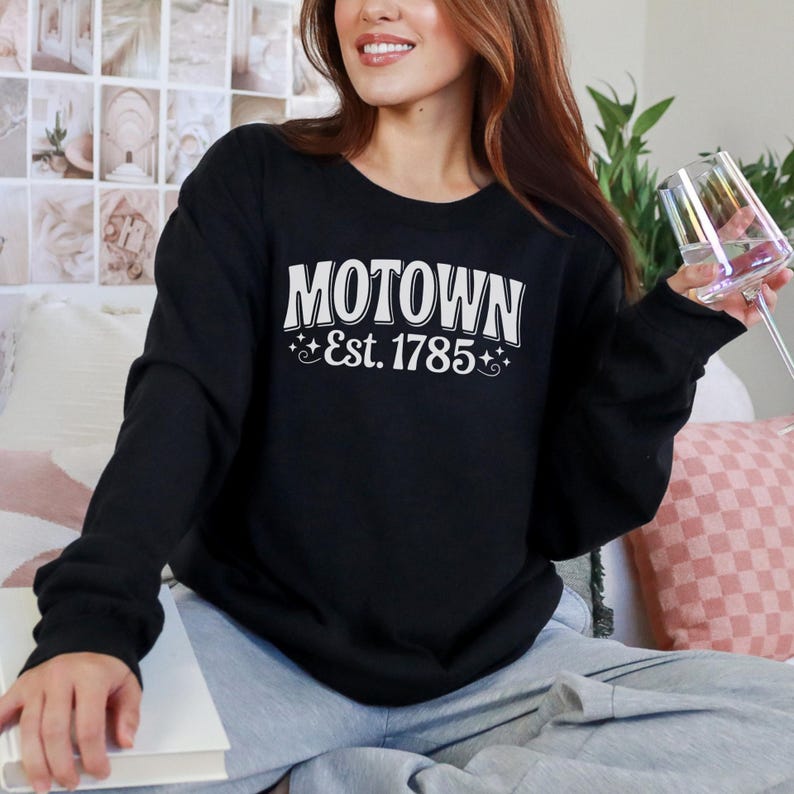 a woman wearing  a black sweatshirt that says "Motown Est 1785" with star graphics. this design is part of  A collection of west virginia vector designs perfect for cricut, silhouette, sublimation, DTF Printing, POD, tshirts, mugs, tote bags and more!