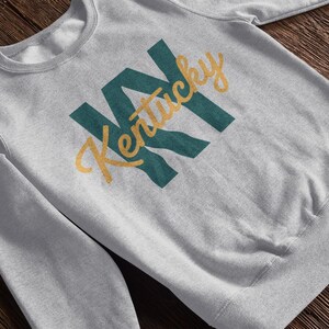 a heather grey sweatshirt that says "KY Kentucky". the design is part of A collection of Kentucky themed vector images perfect for cricut, silhouette, tshirt design, DTF Printing, POD, mugs, tote bags, sublimation and more!