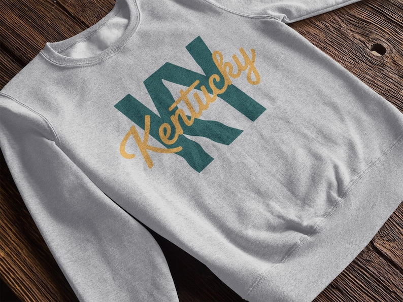 a heather grey sweatshirt that says "KY Kentucky". the design is part of A collection of Kentucky themed vector images perfect for cricut, silhouette, tshirt design, DTF Printing, POD, mugs, tote bags, sublimation and more!