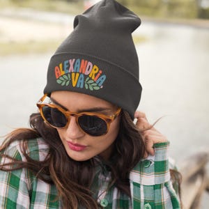 a girl wearing a green flannel shirt and a black beanie that says Alexandria VA in fun colorful text with leaf graphics