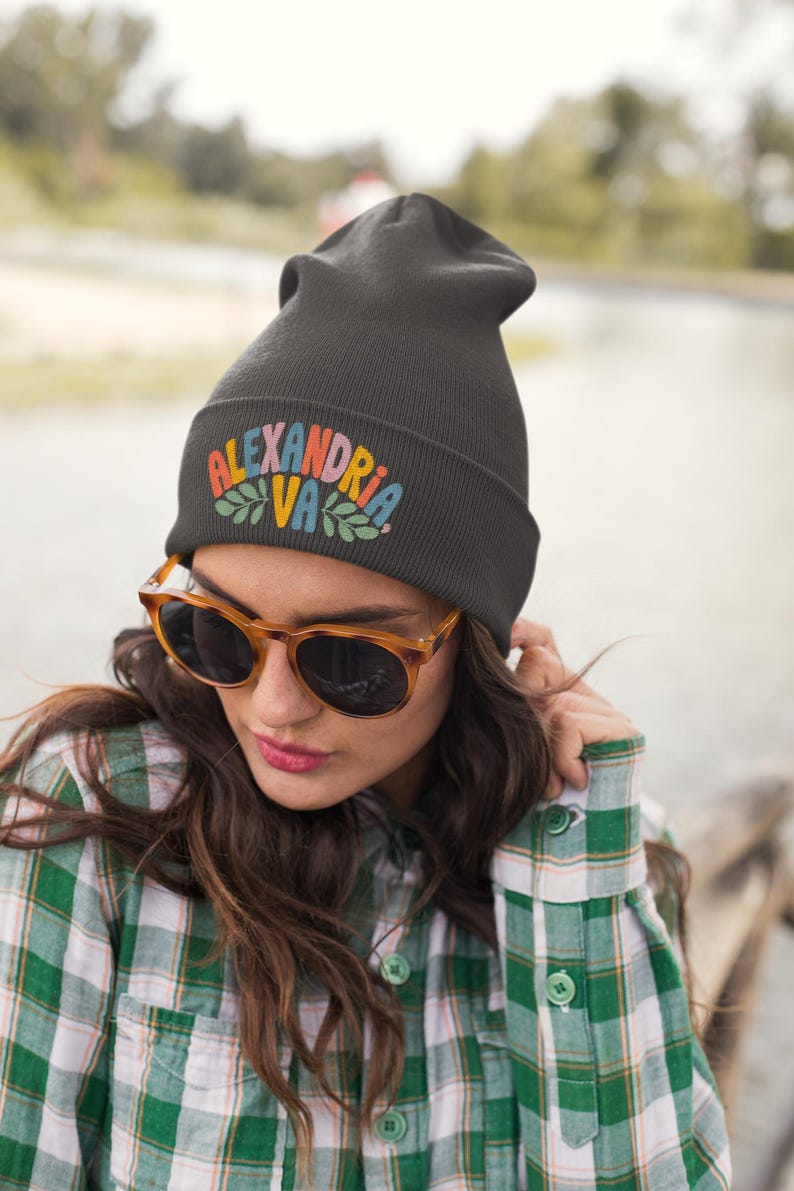 a girl wearing a green flannel shirt and a black beanie that says Alexandria VA in fun colorful text with leaf graphics