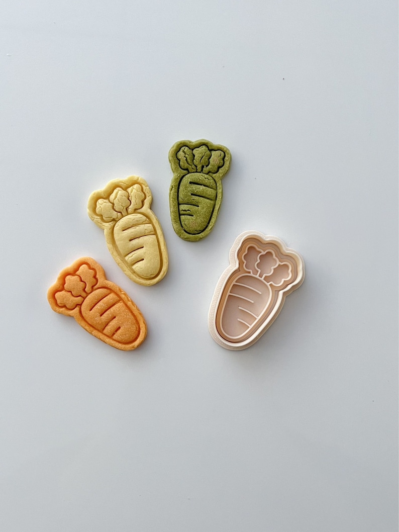 May include: Four cookie cutters in the shape of a carrot. One cutter is green, one is yellow, one is orange, and one is white.
