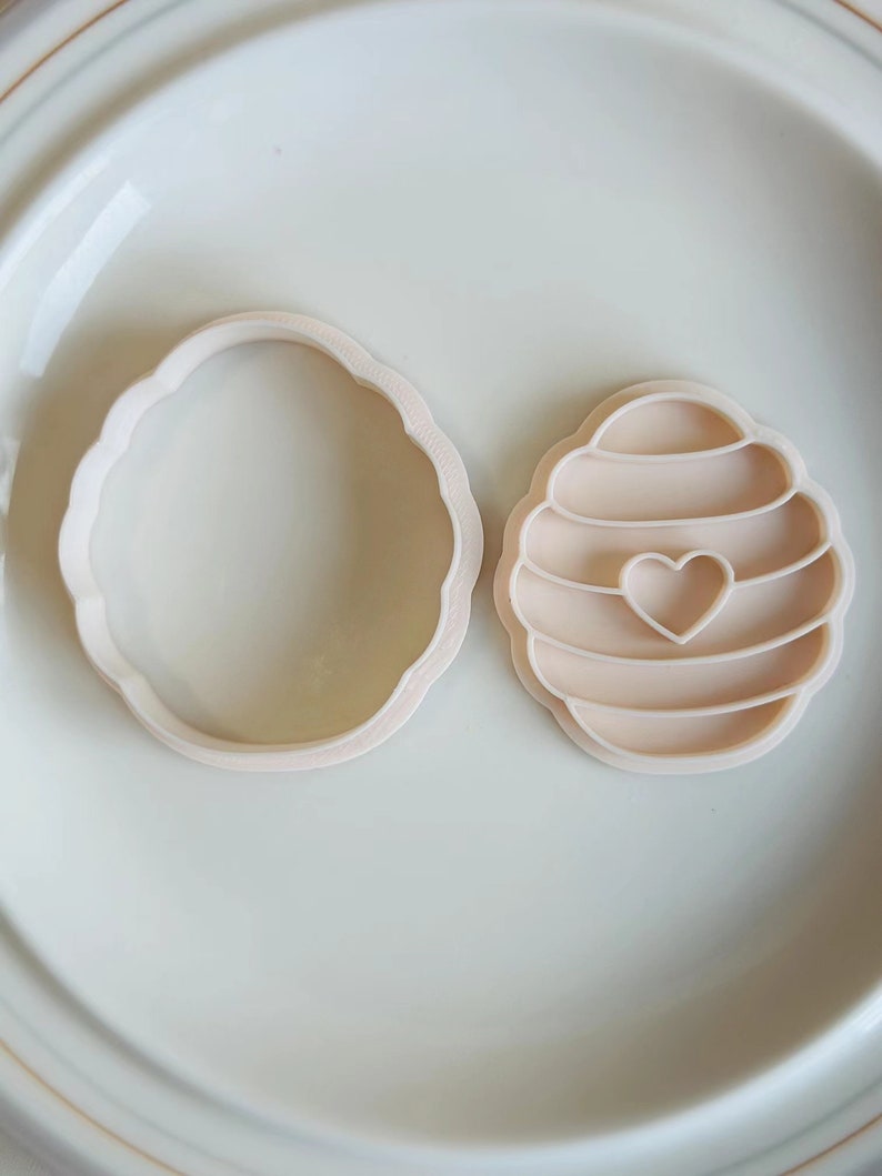 Pu&ograve; includere: Due stampini per biscotti in plastica, uno a forma di favo con un cuore al centro e l'altro a forma di cerchio.