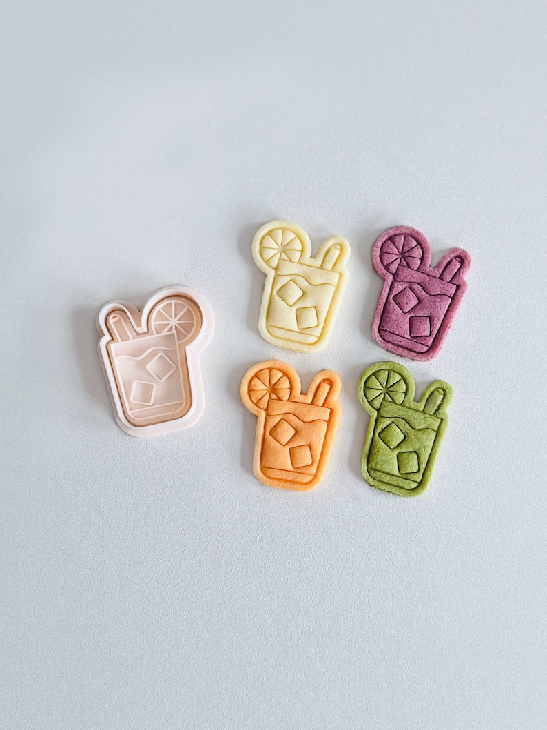 Pu&ograve; includere: Cinque stampini per biscotti a forma di bicchiere di t&egrave; freddo con una fetta di limone e una cannuccia. Gli stampini sono di vari colori: giallo, arancione, rosa, verde e bianco.