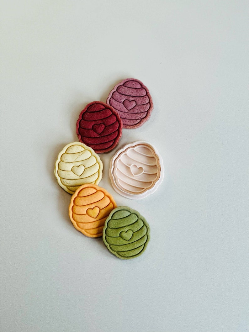 Pu&ograve; includere: Sei stampini per biscotti a forma di favo con un cuore al centro. Gli stampini sono di vari colori, tra cui rosa, rosso, giallo, arancione e verde.