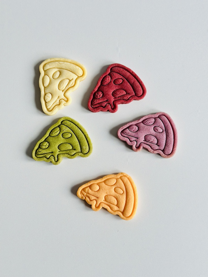 May include: Five pizza-shaped cookies in different colors: yellow, red, green, orange, and purple. The cookies are arranged on a white surface.