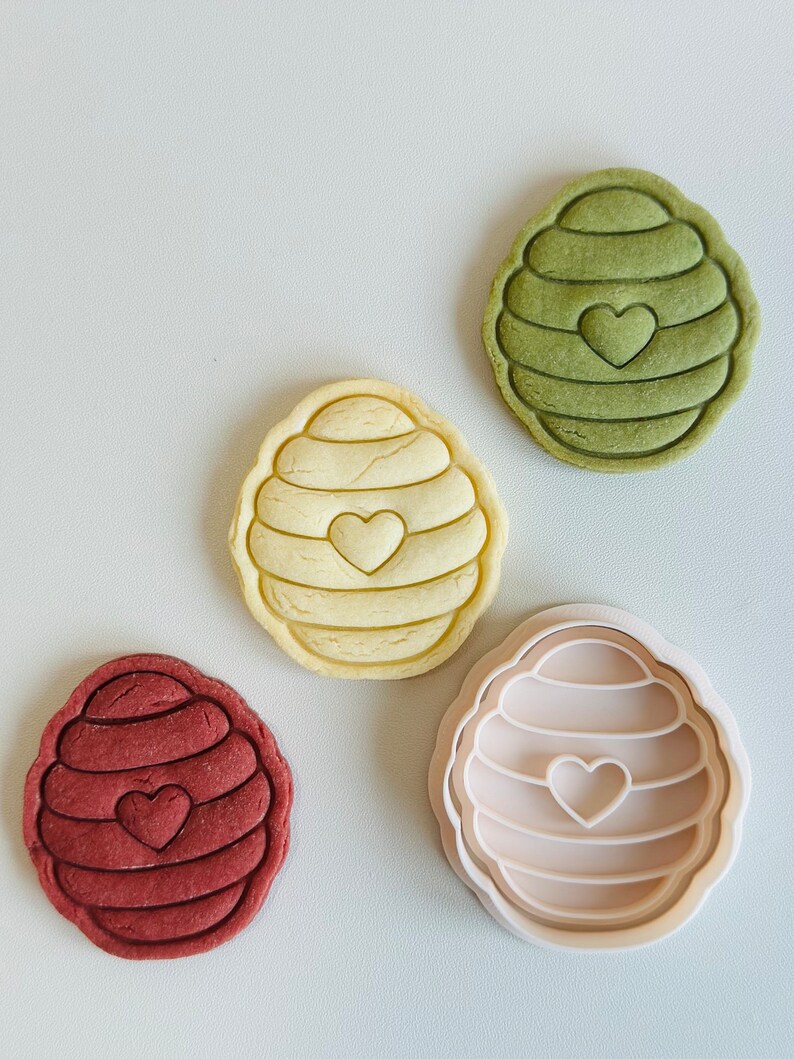 Pu&ograve; includere: Quattro stampini per biscotti a forma di alveare con un cuore al centro. Gli stampini sono di diversi colori: verde, giallo, marrone e bianco.