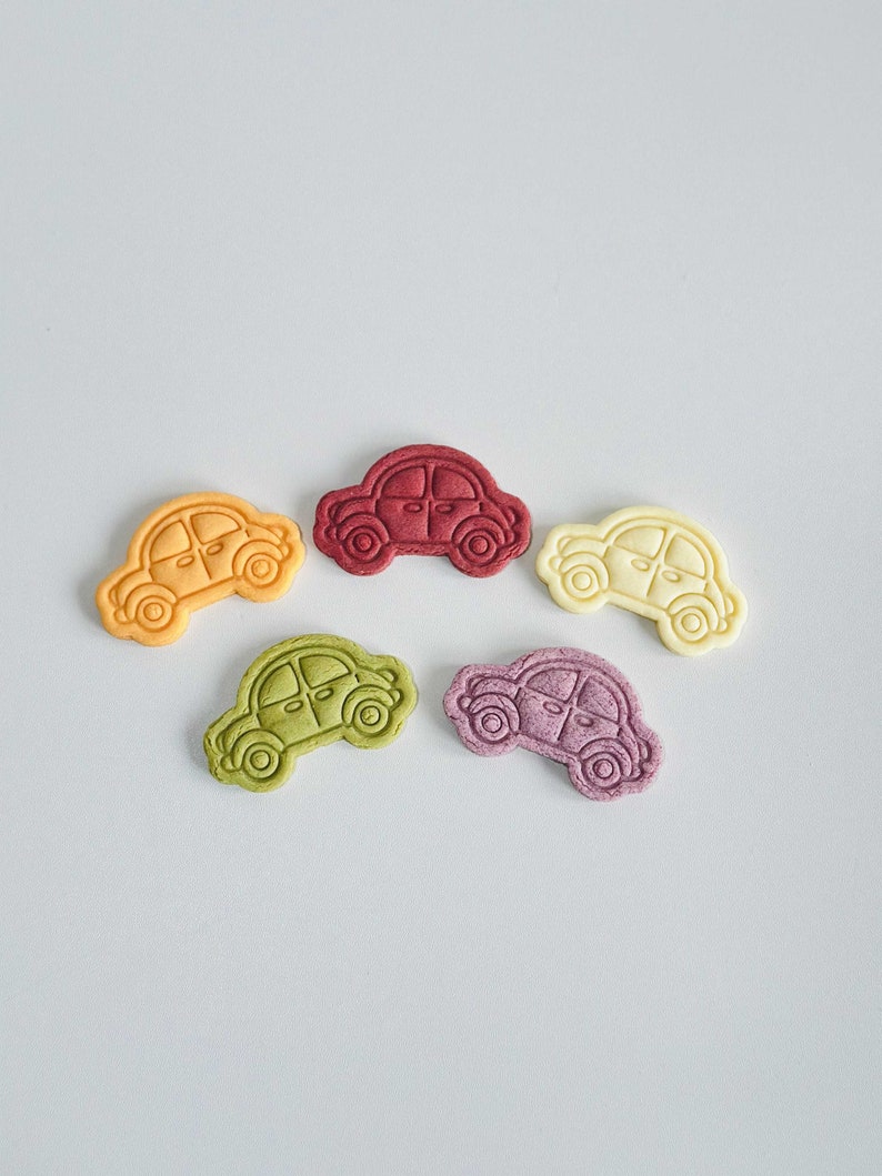 May include: Five small car-shaped cookies in different colors: red, orange, yellow, green, and purple.
