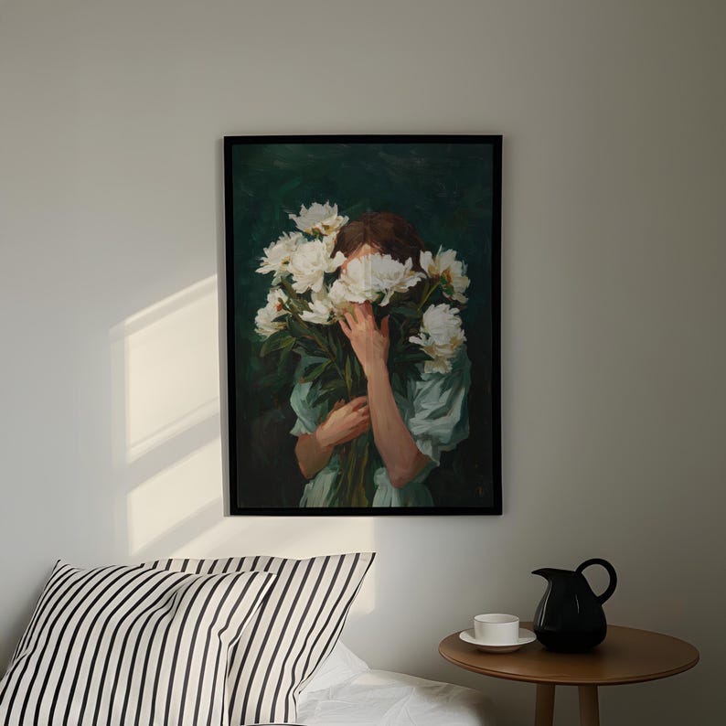 a painting of a woman holding a bouquet of white flowers, hanging on a wall above a bed with a striped pillow.