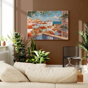 a cozy living room with a large painting of a colorful town hanging on the wall above a beige sofa. The room is decorated with several potted plants, creating a warm and inviting atmosphere.