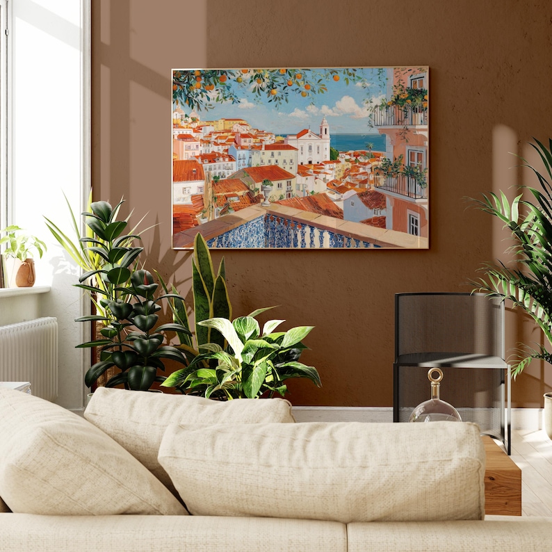 a cozy living room with a large painting of a colorful town hanging on the wall above a beige sofa. The room is decorated with several potted plants, creating a warm and inviting atmosphere.