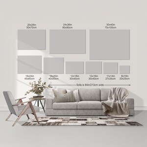 a living room with a gray sofa, a wooden chair, and a rug. There are seven different-sized gray canvas prints displayed on the wall above the sofa, ranging from 20x28in to 30x40in in size. The wall also has a scale indicating the size of the canvas prints, with the largest print being 30x40cm and the smallest being 20x28cm.