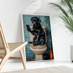 A black dog sitting on a toilet and holding a cell phone in its paw.