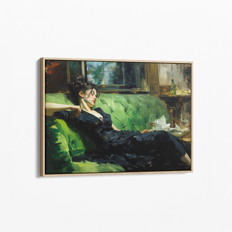 A woman in a black dress is sitting on a green couch, holding a glass of wine.