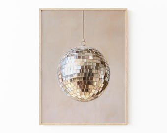 May include: A framed print featuring a disco ball. The disco ball is silver and reflective, composed of many small mirrored squares. It hangs from a thin string against a neutral, light brown background. The frame is a light wood color.