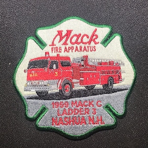 Może przedstawiać: Naszywka haftowana w kolorze czerwonym, białym i zielonym z zieloną obwódką. Przedstawia czerwony wóz strażacki z napisem "Mack Fire Apparatus" i "1959 Mack C Ladder 3 Nashua N.H."