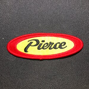 May include: A red and yellow oval embroidered patch with the word "Pierce" in black cursive lettering.