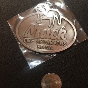 May include: Silver metal keychain with a Mack Fire Apparatus logo. The logo features a bulldog and the text "Mack Fire Apparatus FD.N.Y."