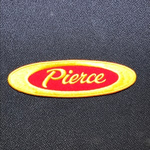 May include: A gold oval-shaped patch with a red interior and the word "Pierce" in a gold cursive font.