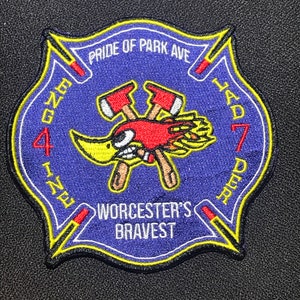 Puede incluir: Un parche bordado azul y amarillo con un pájaro de dibujos animados que lleva un casco de bombero y sostiene hachas cruzadas. El parche dice "Pride of Park Ave" y "Worcester's Bravest" y "Engine 4, Ladder 7".
