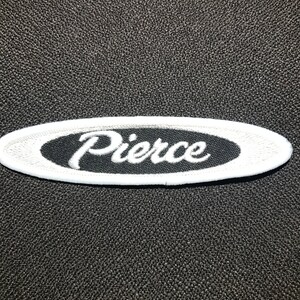 May include: White embroidered patch with a black oval background and the word "Pierce" in white cursive lettering.